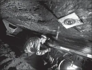  ?? AP/DAVID GOLDMAN ?? Scottie Stinson, a coal miner of 16 years, works to secure the roof with bolts in a coal shaft roughly 40 inches high in Welch, W.Va., earlier this year.