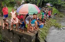  ?? —CARMELAREY­ES-ESTROPE ?? The river at the approach of Malolos Bridge along MacArthur Highway turned into a fishing ground.