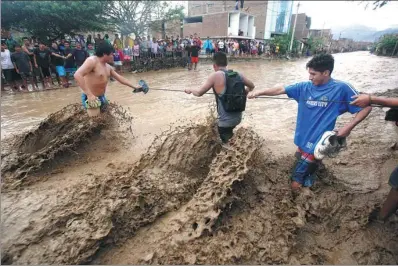  ?? DOUGLAS JUAREZ / REUTERS ?? Residents cross a street after a massive landslide and flood in Trujillo, northern Peru, on Sunday.