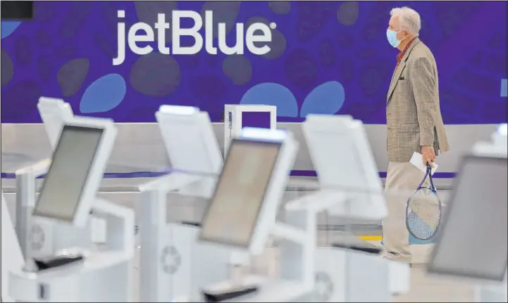  ?? Charles Krupa The Associated Press ?? A traveler wearing a protective mask, due to the coronaviru­s outbreak, walks through the nearly empty Jetblue terminal at Logan Airport in Boston in 2020.