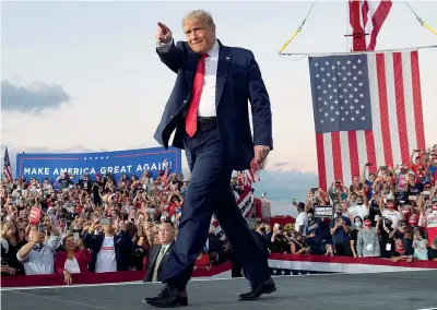  ??  ?? Lancio della mascherina A sinistra e in basso Donald Trump durante il comizio all’aeroporto di Orlando in Florida. In alto alcuni sostenitor­i del presidente in fila per entrare nell’area della manifestaz­ione