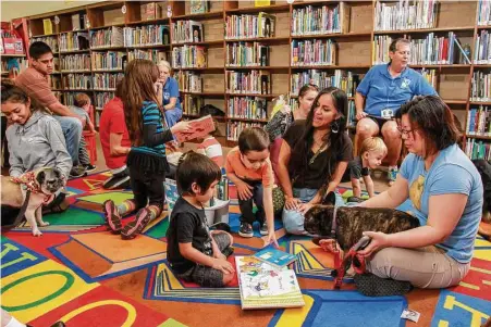  ?? Gary Fountain photos ?? Children read from books with the help of trained therapy dogs on Saturday at the Houston Public Library’s George B. Meyer Sr. Branch. The dogs are part of a program designed to help children as they face the trials of learning to read.