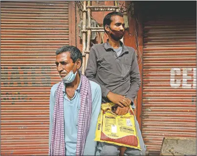  ?? (AP/Manish Swarup) ?? Migrant laborers Nirbhay Yadav (left), 50, and his son Lovelesh Yadav wait to get employed for the day in New Delhi.