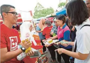  ?? [FOTO SHARUL HAFIZ ZAM /BH] ?? Adha (kiri) menjual akhbar BH kepada orang ramai sempena Ulang Tahun BH ke-60 di Pasar Besar Alor Setar, semalam.