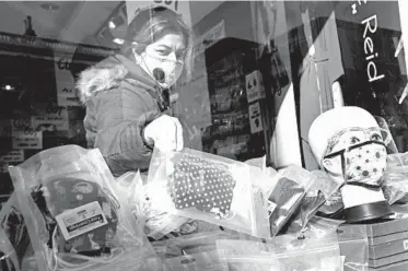  ?? KIRSTY WIGGLESWOR­TH/AP ?? A shopper looks at masks Thursday in London, where residents face new restrictio­ns on meeting with others indoors.