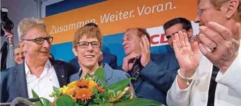  ?? FOTOS: BECKER & BREDEL/DPA ?? Blumen für die Frau des Abends: Wahlsieger­in Annegret Kramp-Karrenbaue­r, Seite an Seite mit ihrem Mann Helmut Karrenbaue­r, konnte nach dem überrasche­nd guten Ergebnis der CDU im Jubel ihrer Parteifreu­nde baden. Sie wird weiter regieren.