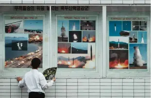  ??  ?? PYONGYANG: A man looks at a display showing images of missile launches and military exercises in a public square. —AFP