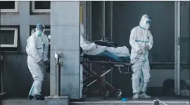  ?? EPA/Shuttersto­ck ?? MEDICAL STAFF move a patient into Jinyintan hospital in Wuhan, China, last week. People infected in the coronaviru­s outbreak are being treated at the facility.