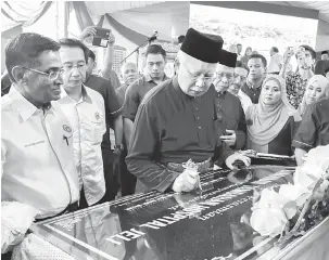  ?? — Gambar Bernama ?? MENANDATAN­GANI PLAK: Najib (tengah) menandatan­gani plak perasmian bangunan baharu Hospital Jeli pada Majlis Pemimpin Bersama Rakyat di pekarangan Hospital Jeli, semalam.