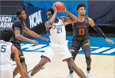  ?? ROBERT FRANKLIN/AP PHOTO ?? UConn’s Adama Sanogo (21) holds the ball between Maryland’s Darryl Morsell, left, and Hakim Hart (13) during the first half of Saturday night’s NCAA first-round tournament game at Mackey Arena in West Lafayette, Ind. Maryland beat the Huskies, 63-54.