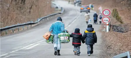  ?? ?? A WOMAN with two children leave Ukraine after crossing the Slovak-ukrainian border in Ubla, eastern Slovakia, close to the Ukrainian city of Welykyj Beresnyj, on February 25, 2022, following Russia’s invasion of the Ukraine. Ukrainians started to flee the conflict in their country a day after Russia launched a military attack on neighbouri­ng Ukraine. | PETER LAZAR AFP