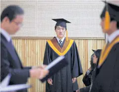  ??  ?? FOREVER DIFFERENT: A high school student who escaped from North Korea waits for his graduation diploma. The two sides are apart even in language.