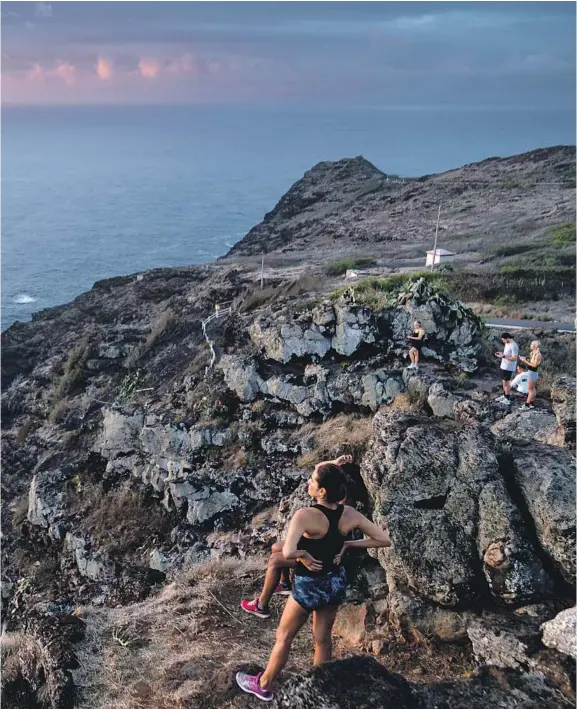  ?? Photog r aphs by Kent Nishimura Los Angeles Times ?? A MOTHER and daughter watch the sunrise from Makapuu Point Lighthouse Trail on Oahu, top; visitors enjoy the ATV Raptor Tour at Kualoa Ranch on the island’s northeaste­rn shore, far left; and surfers launch from Kahanamoku Beach at the west end of Waikiki.