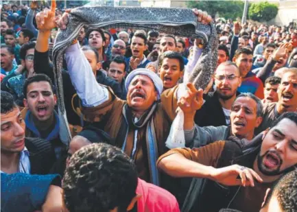  ??  ?? Egyptians shout slogans as they gather outside the Saint Peter and Saint Paul Coptic Orthodox Church in Cairo’s Abbasiya neighborho­od after it was targeted by a bomb. The blast killed at least 25 during Sunday Mass. Mohamed Meteab, AFP