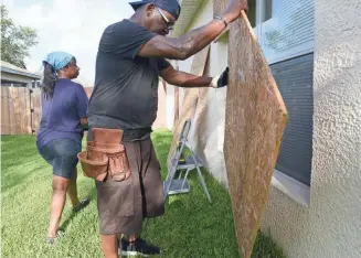  ?? CRAIG BAILEY, FLORIDA TODAY VIA USA TODAY NETWORK ?? Carrie and Ron Wilcox of West Melbourne, Fla., put up shutters Friday in preparatio­n for Hurricane Irma.