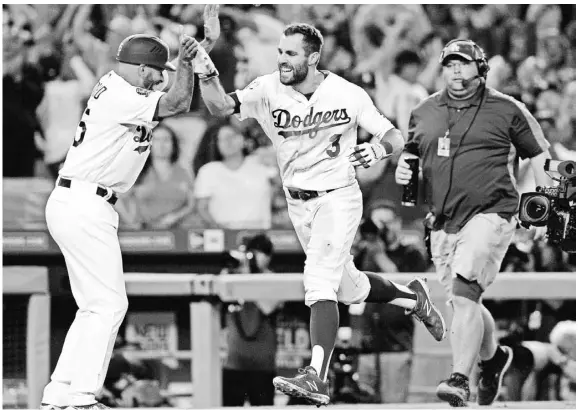  ?? GARY A. VASQUEZ/USA TODAY SPORTS ?? Dodgers left fielder Chris Taylor celebrates with third-base coach Chris Woodward after hitting a walk-off solo home run against the Rockies during the 10th inning Sept. 18 at Dodger Stadium.