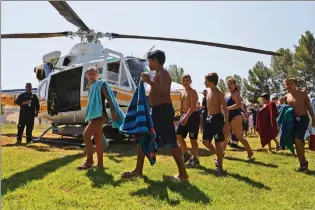  ?? Katharine Lotze/The Signal (See additional photos at signalscv.com) ?? Castaic Lake junior lifeguards walk to the grass before laying out their towels ahead of a presentati­on from the crew of the Los Angeles County Fire Department’s Copter 17 on Tuesday.