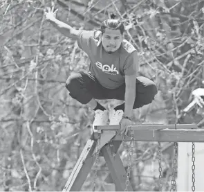  ?? ?? Nepalese national Dinesh Sunar, a parkour athlete, balances on a swing set at his sister-in-law’s North Hill home in Akron.