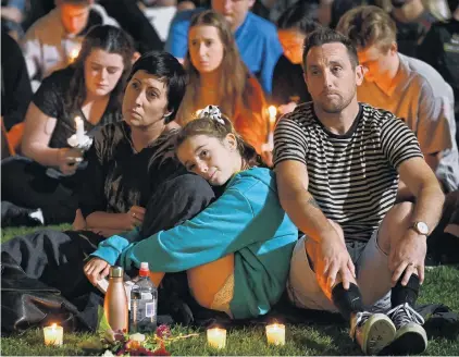  ?? PHOTOS: GERARD O’BRIEN ?? Time to reflect . . . A family burns candles as they listen to the calls for unity, tolerance and respect at last night’s civic vigil.