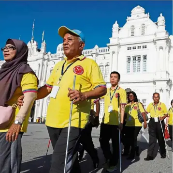  ??  ?? Highlighti­ng their rights: Volunteers leading the blind during the 3.5km walk around the heritage enclave in George Town in conjunctio­n with World White Cane Safety Day.