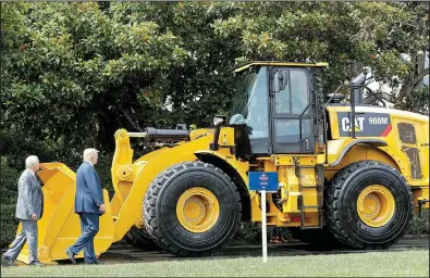  ?? AP/PABLO MARTINEZ MONSIVAIS ?? Vice President Mike Pence (left) and President Donald Trump walk past a Caterpilla­r front-end loader parked Monday on the South Lawn of the White House. Trump’s Made in America event showcased products made in each of the 50 states. Caterpilla­r is...