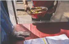  ?? TAMARa MERINO/BLOOMBERG ?? A resident receives a meal in Santiago, Chile. The meals are funded with donations that are starting to stretch thin.