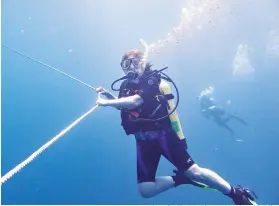  ?? Photo for The Washington Post by John Briley ?? ■ The author's sister, Gina Space, hangs on the "granny line" of the Lion's Paw dive boat during a decompress­ion stop.