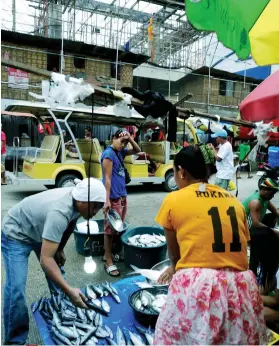  ?? SUNSTAR FILE ?? HAGGLING FOR A BETTER PRICE. Vendors sell fish by the old Mandaue City Public Market while they wait for constructi­on of the new one to be completed.