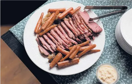  ?? ABEL URIBE/CHICAGO TRIBUNE PHOTOS; SHANNON KINSELLA/FOOD STYLING ?? A peppery maple glaze tops a dish of baked corned beef with caramelize­d onions and carrots.