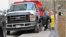  ?? JACK LAKEY/TORONTO STAR ?? A man in a wheelchair tries to get between a fire hydrant and a vehicle on the sidewalk on the south side of Charles St., just east of Yonge St.