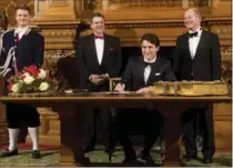  ?? CHRISTIAN CHARISIUS, THE ASSOCIATED PRESS ?? Prime Minister Justin Trudeau signs the golden book next to Foreign Affairs Minister Sigmar Gabriel, left, and Hamburg’s Mayor Olaf Scholz during the St. Matthew’s Banquet in Hamburg, Germany.