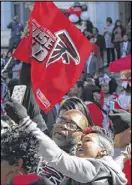  ??  ?? Falcons fans cheer with one another while taking selfies and waving their own flags at a tailgate party put on by the Fulton County government in Atlanta on Tuesday.