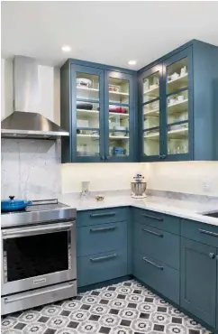  ??  ?? Right: Glass fronts give the floating cabinetry a lighter feel and allow the homeowner to showcase her kitchenwar­e. Rich blue for the cabinetry is paired with a refreshing creaminess on the walls that makes them appear to glow
