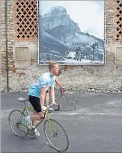  ??  ?? GESTAS. Aficionado­s pasan al lado de una foto de Coppi en Dolomitas.