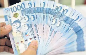  ?? REUTERS ?? A worker shows Philippine peso banknotes at a money changer in Manila.