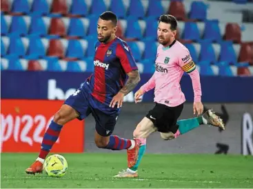  ?? — AFP ?? Eyes on the ball: Barcelona forward Lionel Messi (right) in action against Levante defender ruben Vezo during the La Liga match in Valencia.