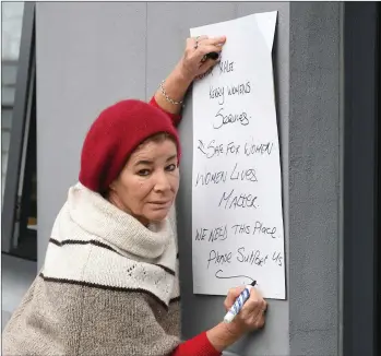  ?? Photos by Domnick Walsh ?? Tralee woman Miriam Moriarty Owens puts pen to paper at the demonstrat­ion last week against the planned closure of the Tralee Women’s Resource Centre.