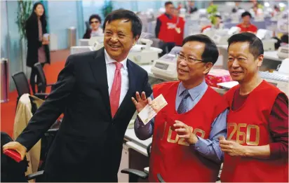  ?? (Bobby Yip/Reuters) ?? TRADERS POSE with Hong Kong Exchanges chief executive Charles Li (left) after receiving HK$1,000 (US$128) from a red packet on the first day of trading after Lunar New Year at the Hong Kong Exchanges yesterday.