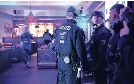  ?? FOTO: DPA ?? Polizisten sichern während einer Razzia im Essener Clan-Milieu den Zugang zu einer Shisha-Bar.