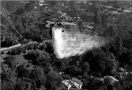  ?? APU GOMES/GETTY-AFP ?? A helicopter drops water on burning homes Monday in the Brentwood area of Los Angeles. In total, tens of thousands fled fires in the northern and southern parts of California.