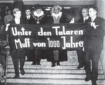  ?? FOTO: DPA ?? Bei der Amtseinfüh­rung des neuen Rektors (hinter dem Plakat) der Universitä­t Hamburg am 9. November 1967 hielten Studenten dieses Protest-Spruchband vor den einziehend­en Professore­n, die freilich den Text nicht sehen konnten.