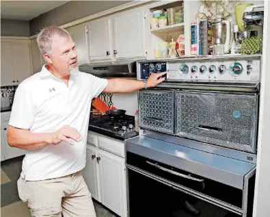  ??  ?? Michael Hopkins, a collector of midcentury modern furnishing­s items, talks about his Frigidaire Flair Custom Imperial range at his home, 3704 N Quapah Circle. Hopkins will be one of the vendors at the Mod Swap during Oklahoma Modernism Weekend.