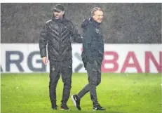  ?? FOTO: SCHLICHTER ?? Gladbachs Trainer Marco Rose (links) und sein Elversberg­er Pendant Horst Steffen stehen nach dem Spiel im strömenden Regen auf dem Rasen.