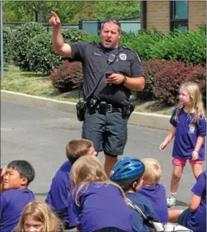  ?? Gazette staff photos by ERIC DEVLIN ?? Upper Dublin police Detective Michael Scarpato points out the incoming helicopter about to fly overhead to Upper Dublin Junior Police Academy campers.