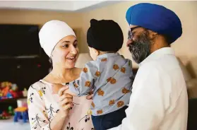  ??  ?? Kavneet Singh, who chairs the Sikh American Legal Defense and Education Fund, and his wife, Karen Singh, spend time with their 14-month-old son at their home in Danville.
