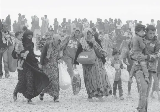  ?? KHALIL MAZRAAWI / AFP / GETTY IMAGES ?? Syrian refugees wait to enter Jordan, east of Amman, in 2016. Jordan, a poor country, has seen its resources and trading economy damaged by the refugee influx.