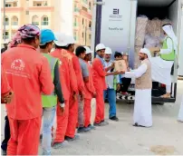  ??  ?? Officials from Beit Al Khair Society distribute meals to workers.