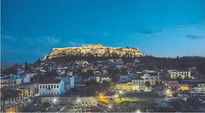  ?? EIRINI VOURLOUMIS THE NEW YORK TIMES ?? The Acropolis, seen from afar in Athens is a great place to see the ancient Greek ruins and indulge in Mediterran­ean food.