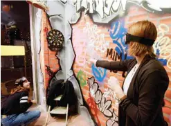  ??  ?? A woman plays darts with special glasses simulating heavy drunkennes­s at the entrance of the Museum of Hangovers.