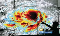  ?? (Manny Llanes) ?? WEATHER DISTURBANC­E – Quezon City Disaster Risk Reduction and Management Office (QCDRRMO) staff JB Basit points out the extent of Typhoon Bising on a huge monitor. ‘Bising’ entered the Philippine Area of Responsibi­lity (PAR) on Friday morning April 16, 2021.